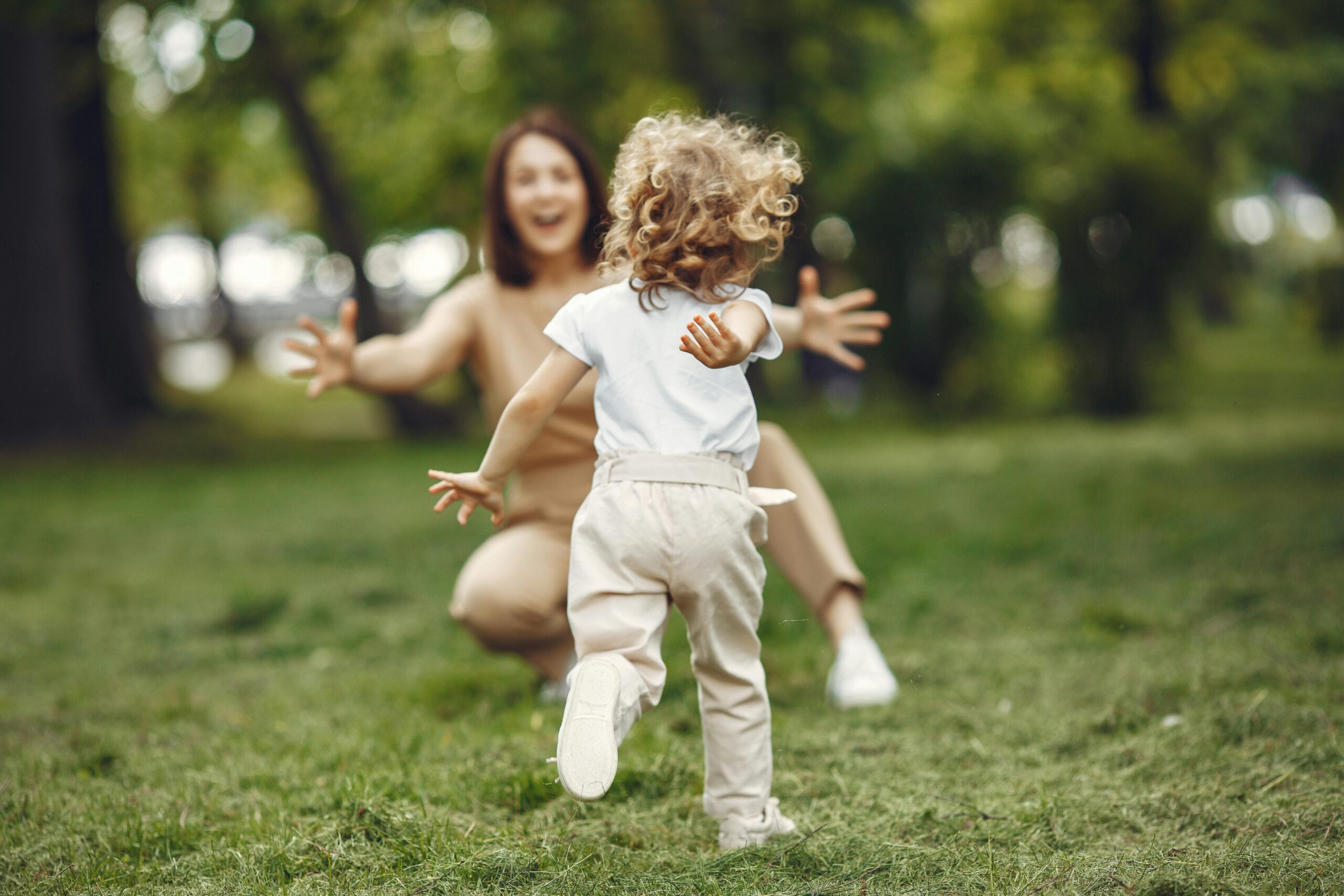 Happy child running to embrace a parent in a lush green park, showcasing love and joy.