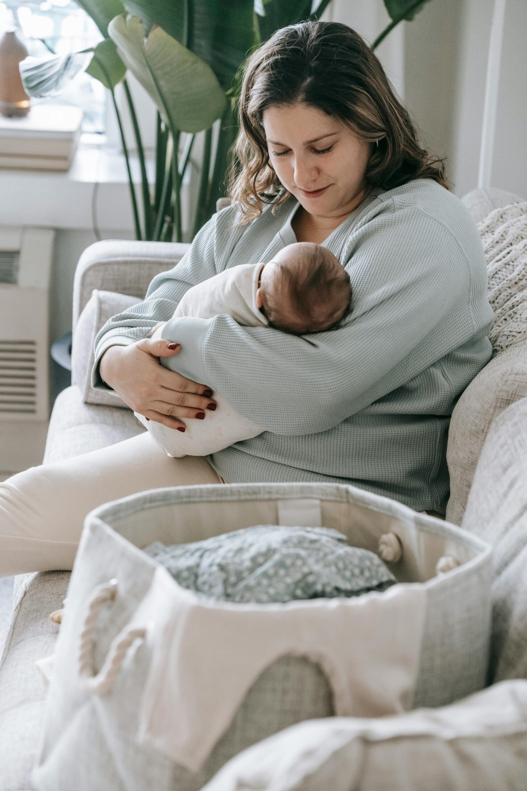A tender moment of motherhood as a mother cradles her newborn baby indoors in a cozy living room setting.